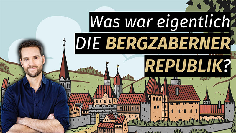 Mirko Drotschmann vor dem Hintergrund der Comiczeichnung von Simon Schwartz Bergzaberner Republik. Mit dem Titel "Was war eigentlich DIE BERGZABERNER REPUBLIK?"