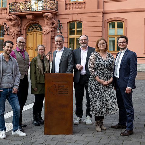 Zu sehen ist das Pult. Daneben und dahinter stehen 7 Personen.